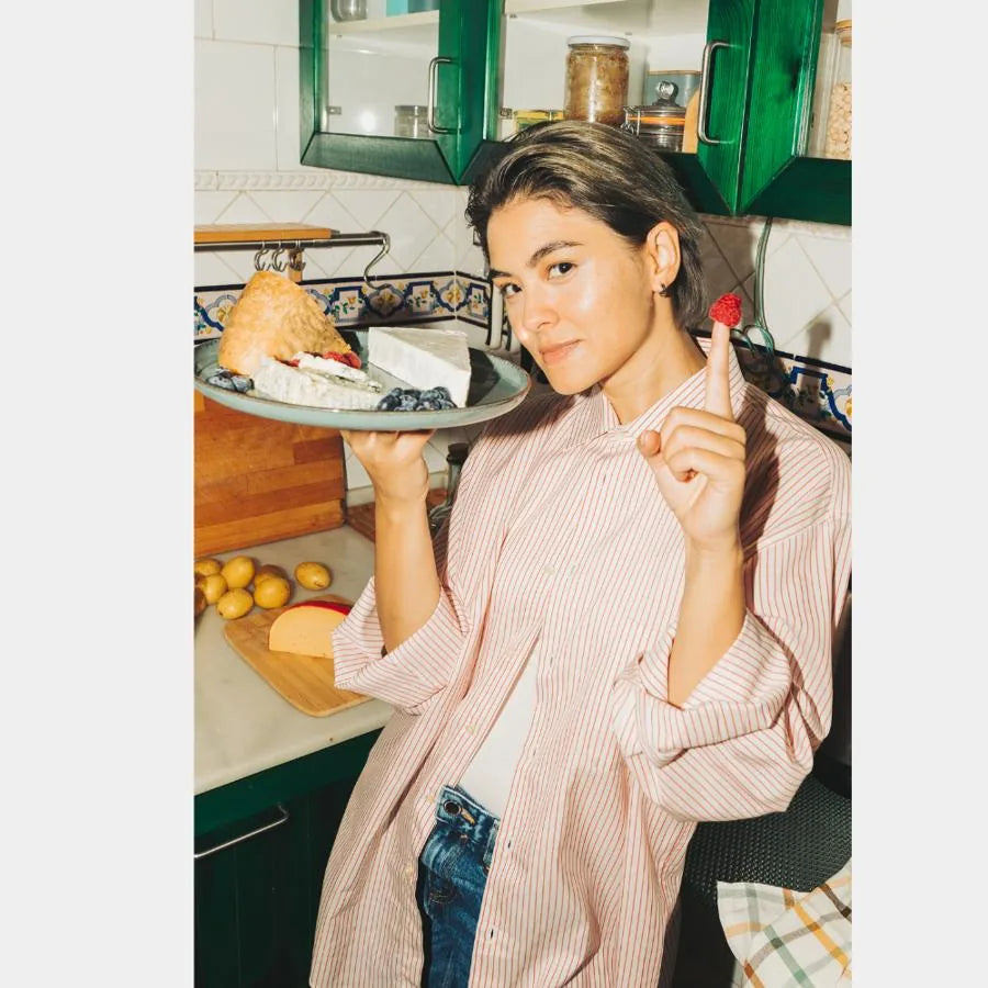 Woman holding a plate of cheese and bread in a kitchen
