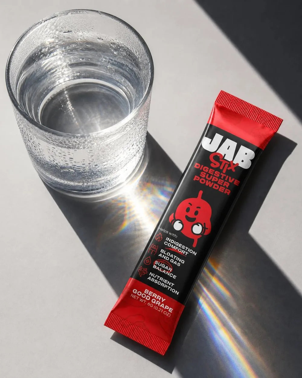A JAB Stix stick pack next to a glass of water
